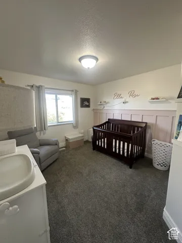 Bedroom featuring wall-to-wall carpeting, board and batten wainscoting, and a flush-mount ceiling light fixture