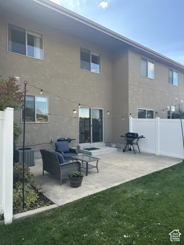 Concrete patio featuring a low-profile step, enclosed by white vinyl privacy fencing and bordered by a manicured lawn