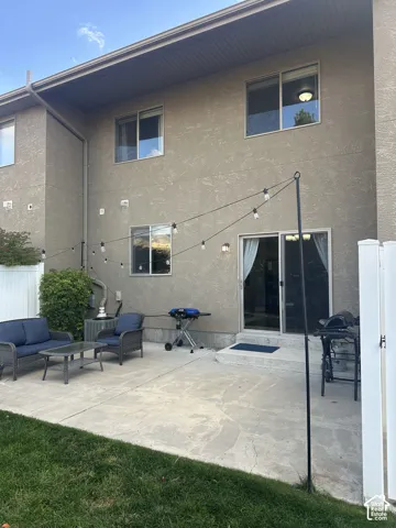 Stucco exterior featuring a concrete patio, sliding glass door, and vinyl privacy fencing