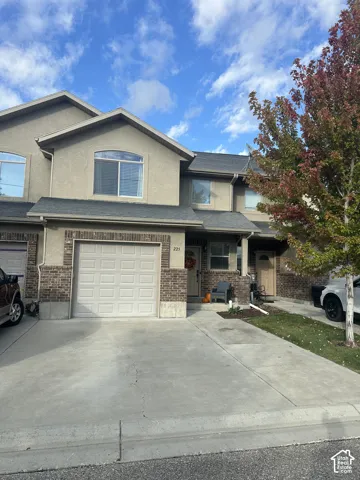 Stucco exterior featuring brick veneer accents, a concrete driveway, an attached garage, and multiple arched windows