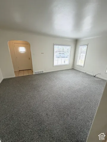 Neutral wall tones, wall-to-wall carpeting, arched entryway, multi-pane windows, and tiled entryway flooring