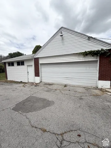 Detached garage featuring white siding, red brick accents, and a wide sectional garage door