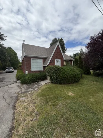 Brick exterior featuring a steep-pitched roofline and mature landscaping