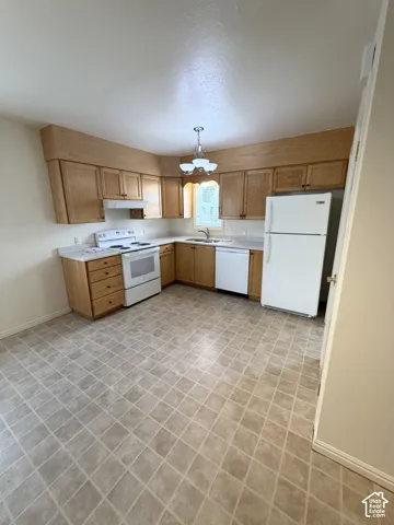 Kitchen featuring light-finish wood cabinetry, solid-surface countertops, stainless steel sink with a goose-neck faucet, and checkered tile flooring