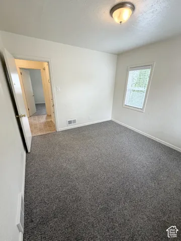 Neutral-toned interior room featuring wall-to-wall carpeting, a multi-pane window with blinds, and a dome-style flush-mount ceiling light fixture