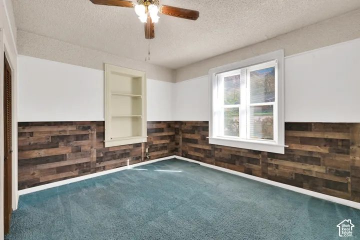 Room interior featuring horizontal wood-plank wall treatments, a built-in recessed wall niche, and a multi-light ceiling fan