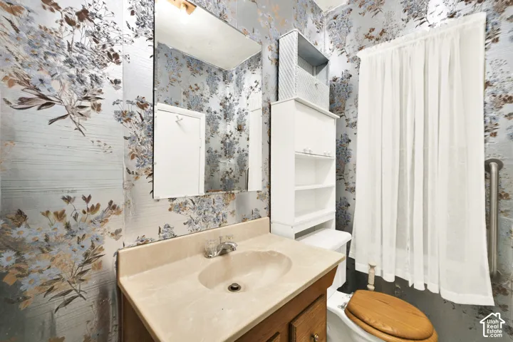 Vanity featuring a light-toned countertop with an integrated oval sink, wall-mounted mirror, built-in shelving unit, and wall-mounted metal support bar