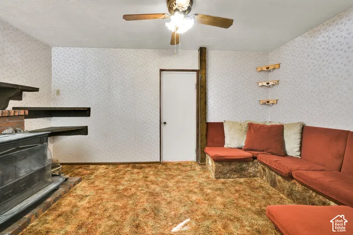 Built-in masonry seating, integrated wood-burning stove, tiered wall shelving, and ceiling fan with multi-light fixture