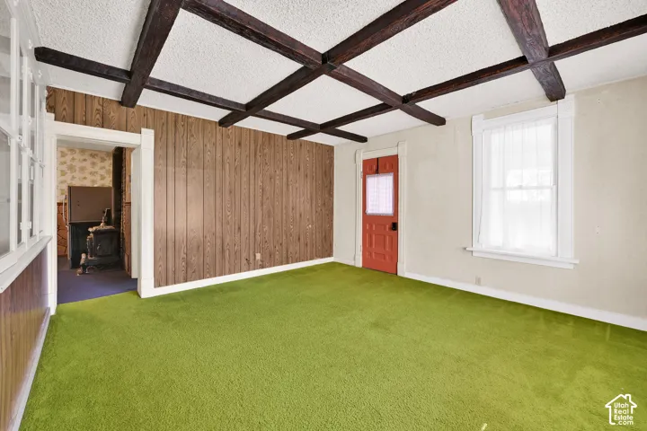 Exposed dark wood ceiling beams, vertical wood-paneling accent wall, and single-pane window with traditional trim