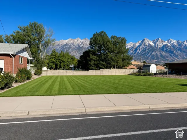 Expansive lawn featuring mature trees, a concrete perimeter wall, and mountain backdrop