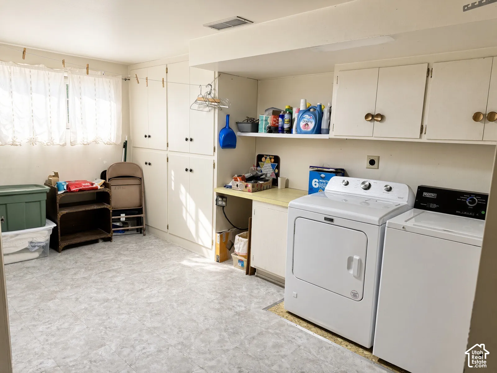 Laundry area featuring floor-to-ceiling cabinetry, ample counter space, open shelving, and resilient vinyl flooring