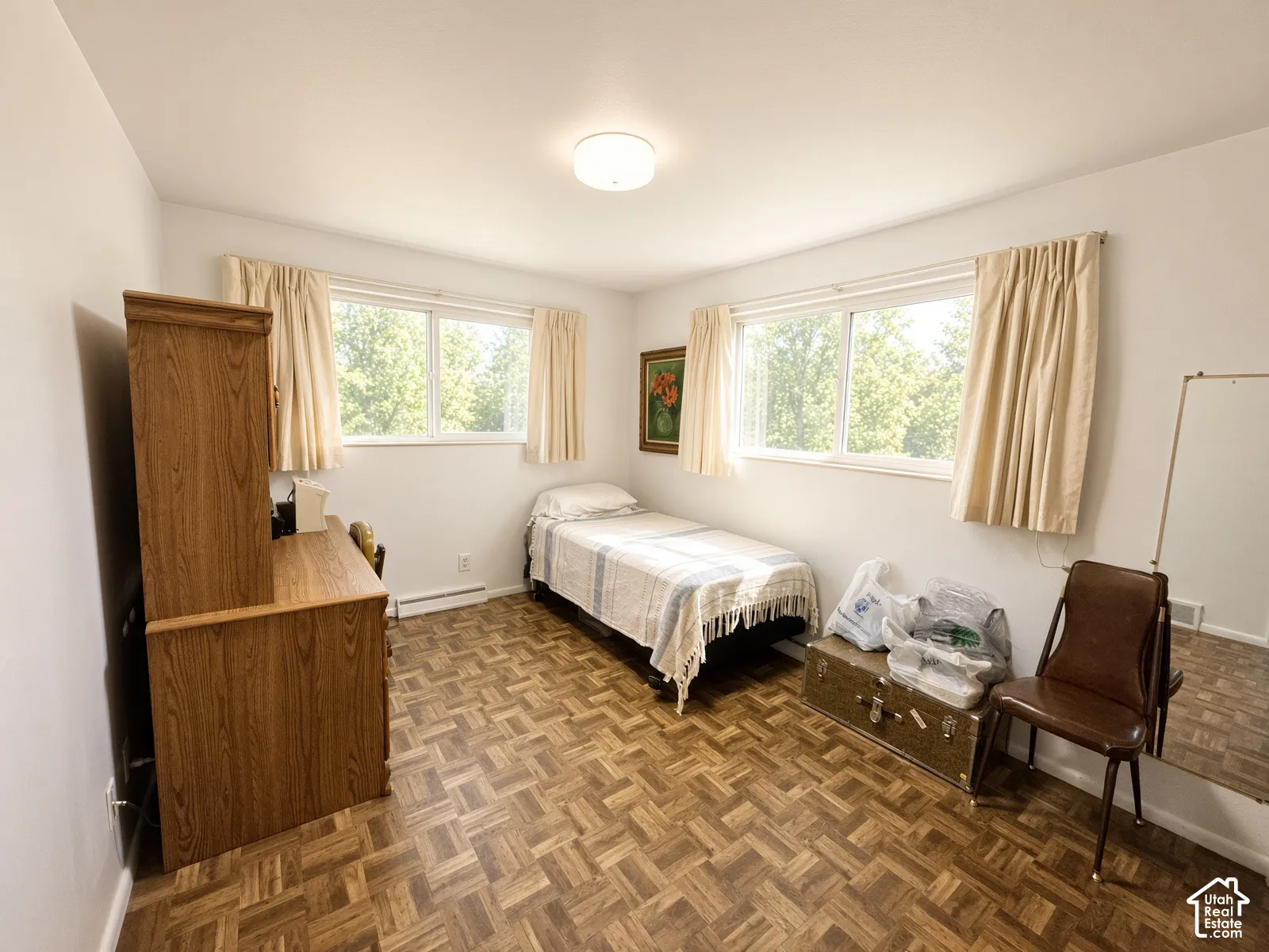 Parquet wood-finish flooring, dual windows with natural light, and a central ceiling-mounted light fixture