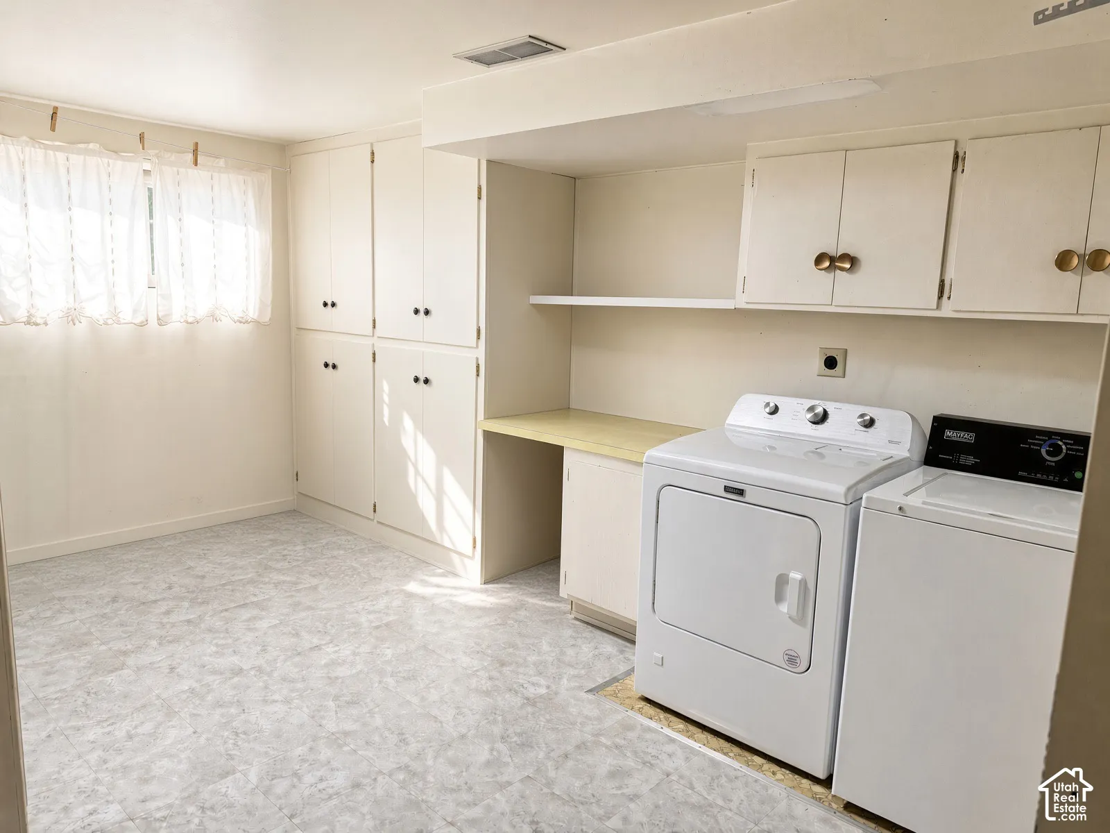 took off cleaning supplies- Utility space featuring extensive floor-to-ceiling built-in cabinetry, an integrated folding counter, additional overhead storage, and vinyl flooring