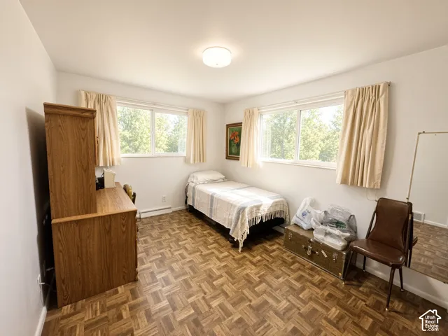 Parquet wood-finish flooring, dual windows with natural light, and a central ceiling-mounted light fixture