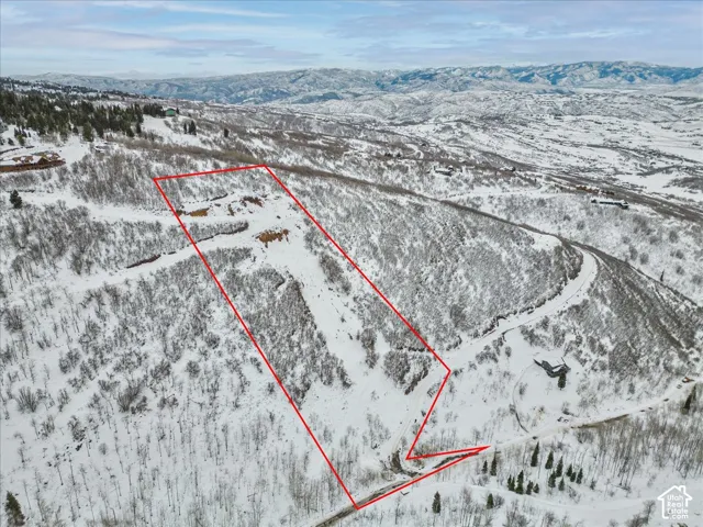 Expansive sloped lot featuring mountainous terrain, mature deciduous trees, and sweeping mountain range horizons