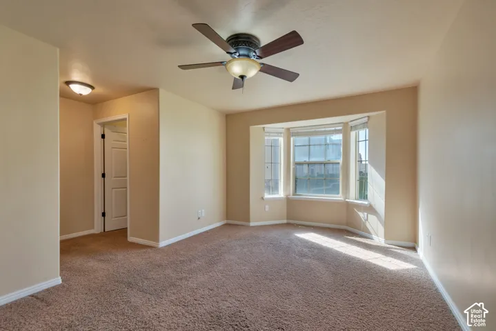 Multi-pane bay window, ceiling fan with integrated lighting, recessed lighting, and neutral wall-to-wall carpeting