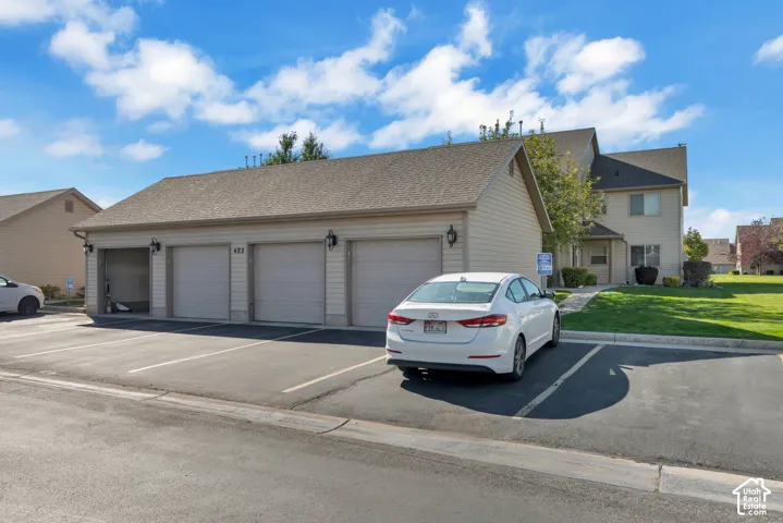 Multi-unit building featuring tan horizontal siding, a pitched asphalt shingle roof, and a three-car garage with individual roll-up doors