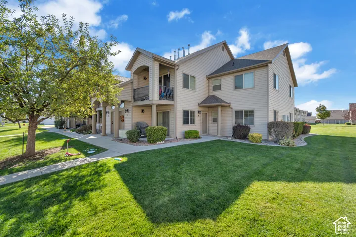 Two-story multi-unit exterior featuring vinyl siding, an upper-level balcony with metal railing, and concrete walkways set within landscaped grounds