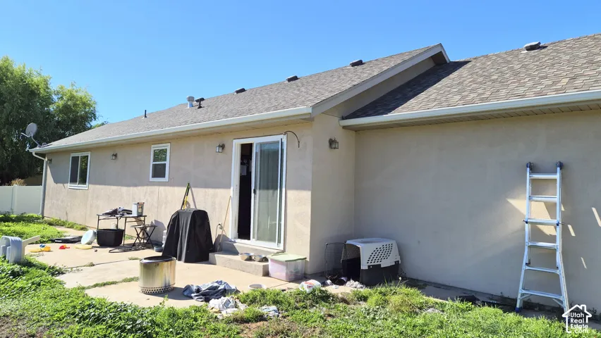 Stucco exterior featuring a concrete patio and a sliding glass door