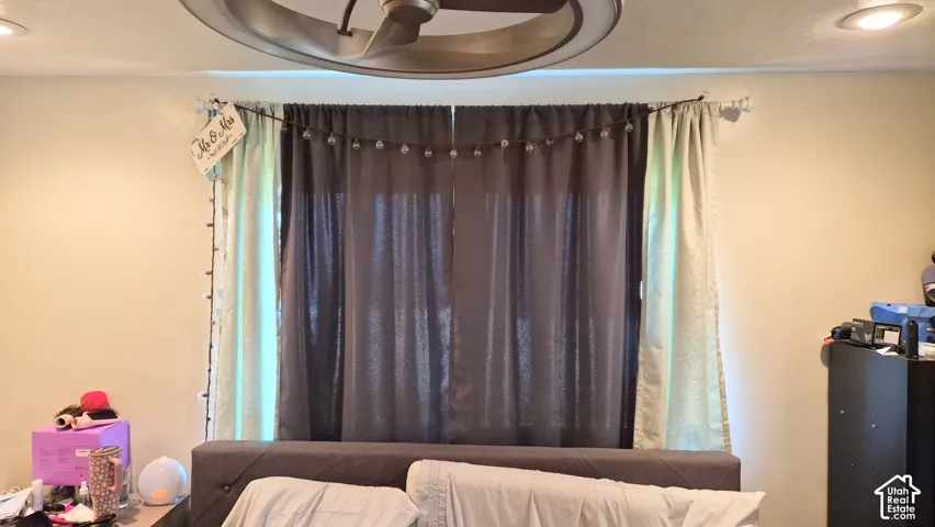 Multi-pane window featuring a rod-mounted drapery system, recessed ceiling lighting, and a dual-blade ceiling fan