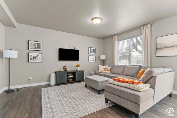 Living area featuring wood-finish flooring, neutral wall paint, and a large window with horizontal blinds