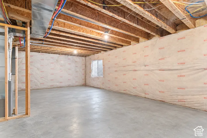 Unfinished lower level featuring exposed wood joist ceilings, concrete flooring, insulated perimeter walls, and a recessed window