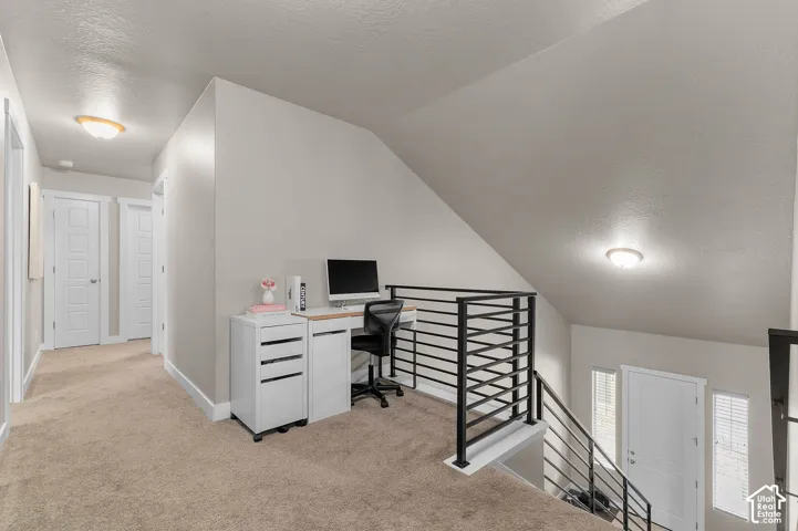 Open landing area featuring neutral carpeting, matte black metal railing, and recessed ceiling lighting