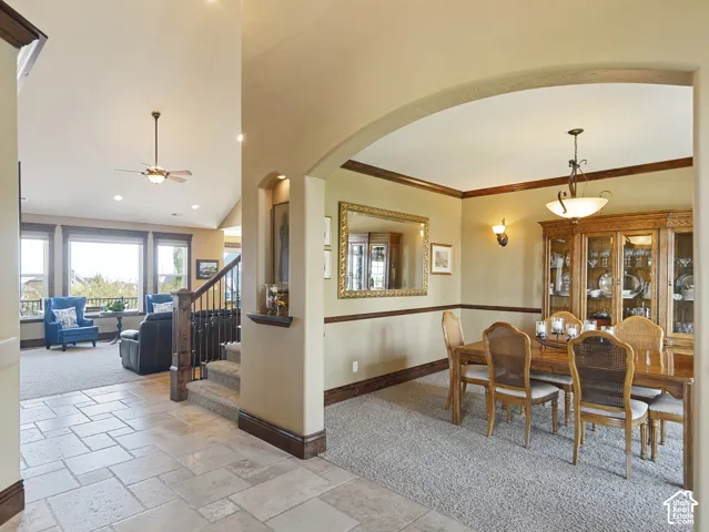 Foyer featuring neutral stone flooring, arched architectural detailing, built-in display niche, crown molding, and wrought iron staircase balusters