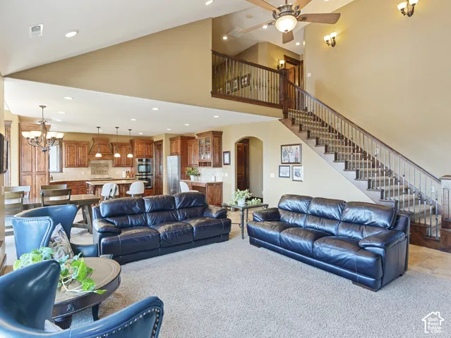 Vaulted ceiling, open-concept kitchen with wood cabinetry, staircase with decorative metal railing, recessed lighting, and a multi-level floor plan