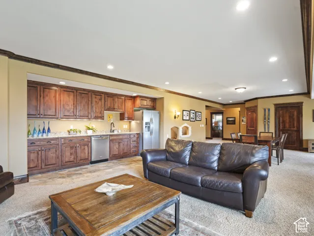 Built-in wet bar featuring stained wood cabinetry, stone countertops, stainless steel undermount sink, dishwasher, and refrigerator