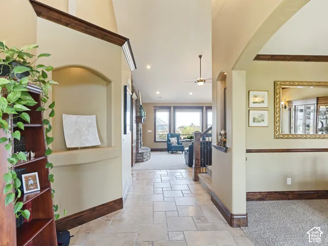 Interior entryway featuring stone tile flooring, vaulted ceilings, arched wall niches, recessed lighting, and dark wood trim