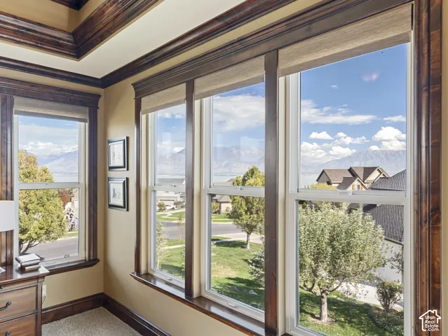 Detailed wood window trim, tray ceiling with stained wood crown molding, and large-format windows featuring mountain and water scenery