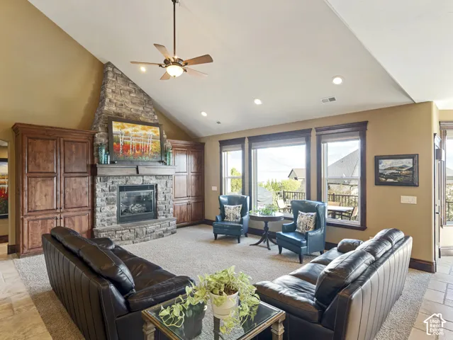 Vaulted ceiling with recessed lighting, stone-surround fireplace, and custom built-in wood cabinetry
