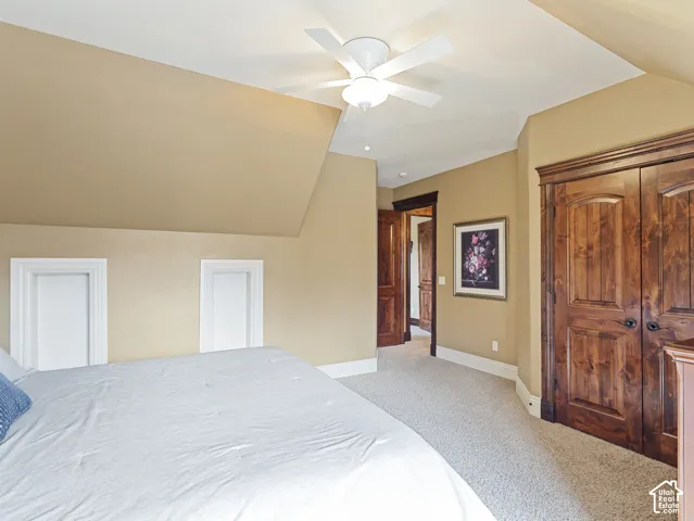Vaulted ceiling, built-in wall niches, stained wood-finish doors with matching trim, and a ceiling fan with integrated lighting