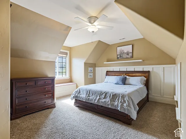 Vaulted ceilings with architectural roof pitches, white wainscoting detail, built-in window seating, and a ceiling fan with integrated lighting
