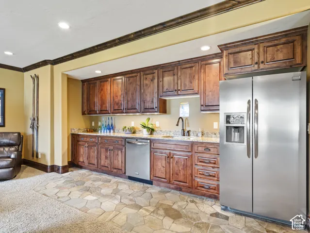 Kitchenette featuring stained wood cabinetry, stone-surface countertops, recessed lighting, flagstone flooring, and stainless steel appliances including a side-by-side refrigerator