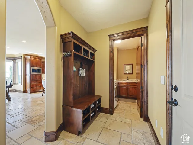 Entryway featuring natural stone tile flooring, built-in dark wood cabinetry with integrated seating and storage, and arched architectural detailing