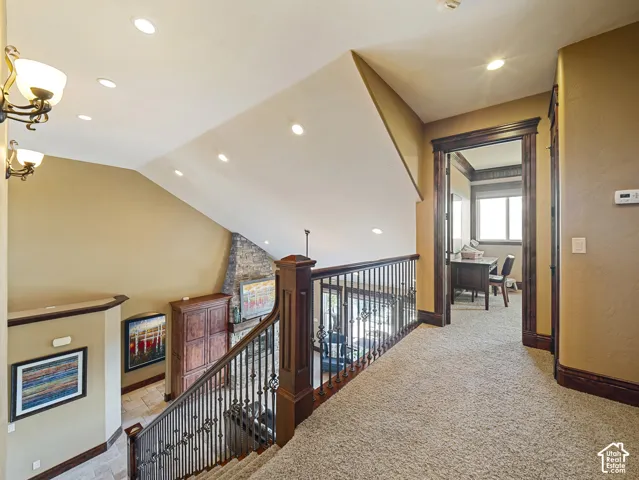 Interior landing featuring a dark wood staircase railing with metal balusters, crown molding, recessed lighting, and dual wall-mounted light fixtures