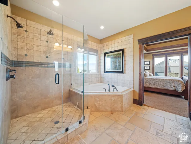 Walk-in shower with a glass enclosure, dual showerheads, and decorative tile accents, paired with a built-in soaking tub featuring stone tile surround and tile flooring