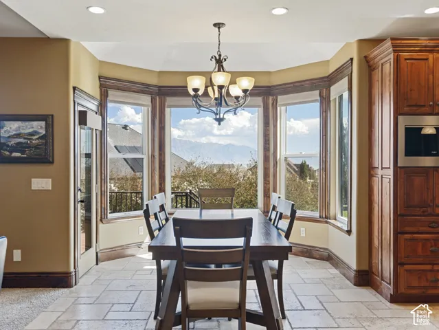 Bay window with expansive mountain scenery, tile flooring, built-in floor-to-ceiling cabinetry, recessed lighting, and an ornate multi-arm chandelier