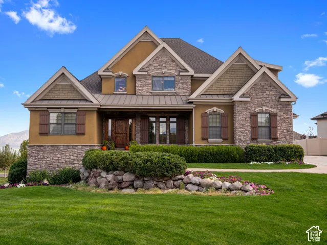 Multi-gabled exterior featuring stone and stucco siding, shingle-style accents, decorative shutters, and a natural stone retaining wall