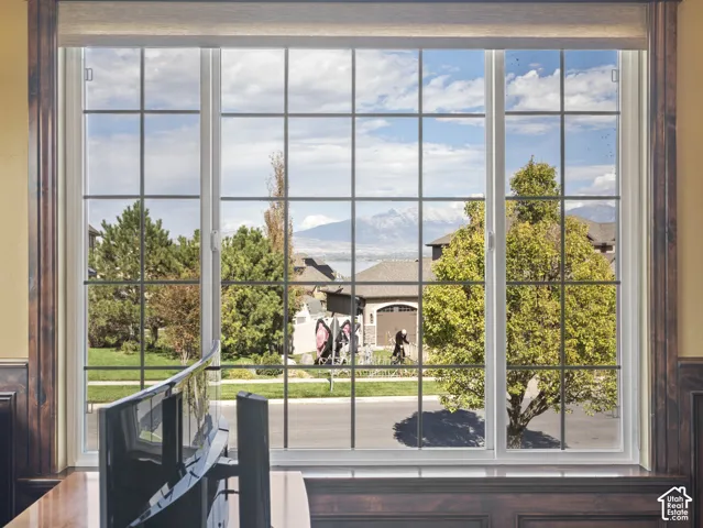 Expansive three-panel window featuring a grid pattern, dark wood trim, built-in wooden sill, and mountain scenery
