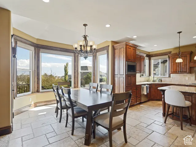 Kitchen featuring natural stone tile flooring, custom cabinetry with integrated microwave, stone-finish countertops, and an expansive bay window with recessed lighting