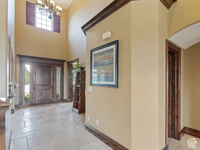Entryway featuring high ceilings, natural stone flooring, dark wood-finish crown molding, a multi-pane window, and a solid wood entry door with side windows