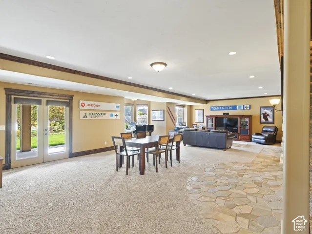 Open-concept room featuring wall-to-wall carpeting, natural stone tile flooring, recessed ceiling lighting, and double glass-paneled doors with wood-finish trim