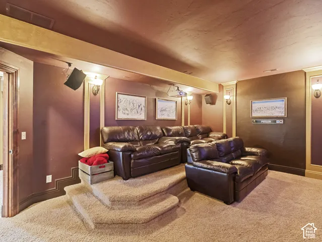Multi-tiered carpeted platform, wall-mounted projector, integrated audio speakers, and decorative wall-mounted light fixtures