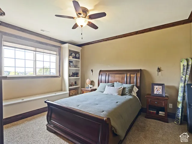 Custom built-in shelving, expansive window seat with storage, crown molding, and ceiling fan with integrated lighting