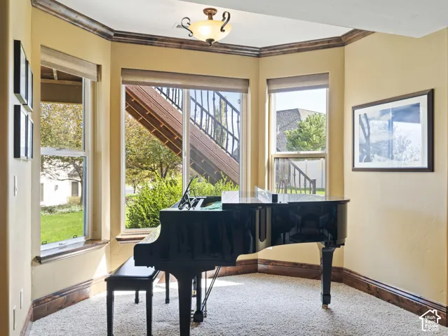 Bay window featuring natural light, stained wood trim, wall-to-wall carpeting, and a semi-flush mount ceiling fixture