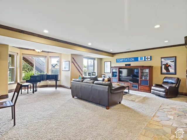 Spacious room featuring recessed lighting, bay windows, built-in wooden media cabinetry, and stone flooring accents