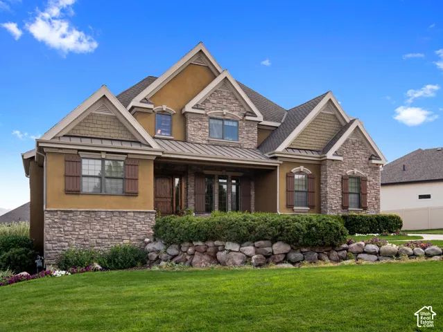 Multi-gabled exterior featuring stone veneer, stucco siding, decorative shakes, metal roofing accents, and a natural stone retaining wall